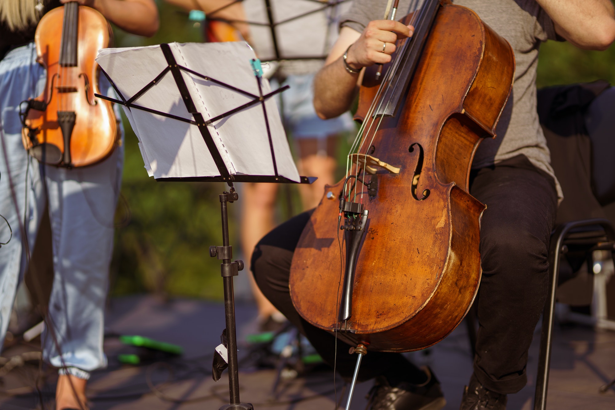 Male violoncellist playing in orchestra at outdoor concert